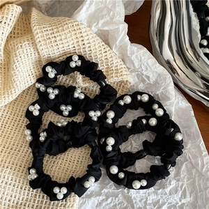 Detailed view of 5-piece black satin hair scrunchies with elegant white faux pearl beads