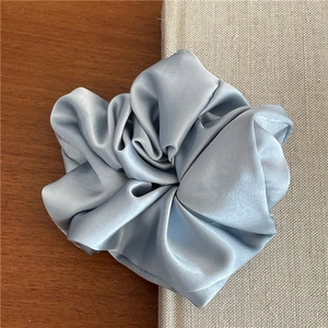 Detail of soft satin blue scrunchie showing smooth fabric texture and rich folds on book