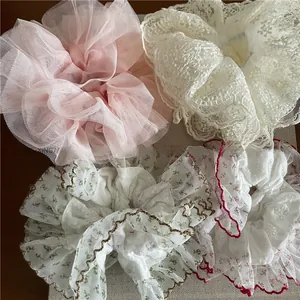Détail de quatre chouchous assortis en dentelle, résille et mousseline à motifs floraux