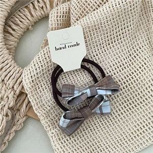 Detail of plaid bow hair ties on card packaging with hand made text and woven background
