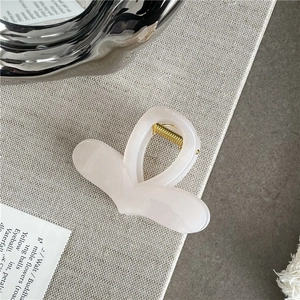 Detail view of a translucent pink heart-shaped hair claw clip with golden spring mechanism