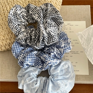 Detail showing checkered and striped fabric hair scrunchies with delicate flower embroidery