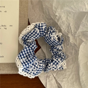 Close-up of blue gingham scrunchie with delicate lace edges on aesthetic background