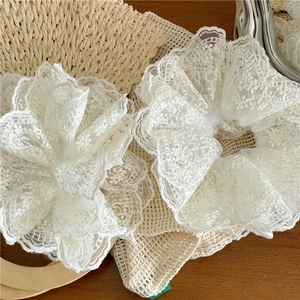 Gros plan de deux chouchous en dentelle blanche avec broderie sur fond en paille tressée
