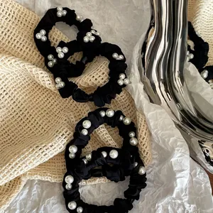 Elegant black satin scrunchie with white pearl clusters for a stylish ponytail look