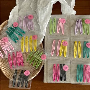 Colorful matte metal BB hair clip set in transparent packaging on a wooden desk