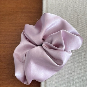 Close-up of premium lilac satin scrunchie showing detailed silk texture on a wooden table