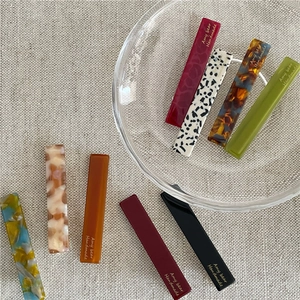 Close-up of rectangle acetate hair clips with colorful marble texture and handmade logo