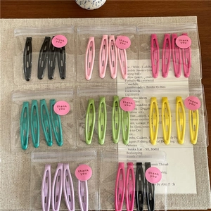 Close-up of candy-colored metal snap hair clips set on beige linen background