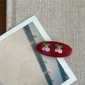 Détail de la pince à cheveux cerise rouge foncé avec strass roses et émail vert