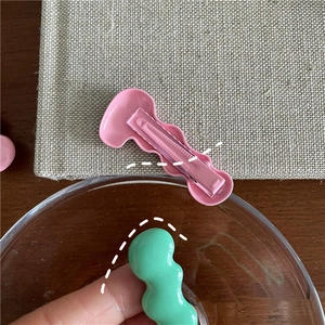 Detail of pink and mint green wave hair clips showing metal alligator clip mechanism