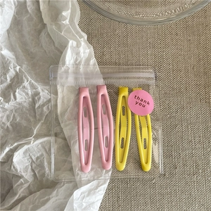 Close-up of pink and yellow matte teardrop hair clips in thank you packaging