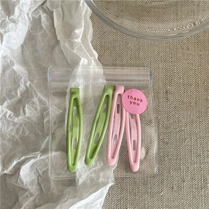 Close-up of pastel hollow hair clips in macaron green and pink colors in a poly bag
