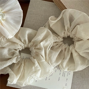 Détail du chouchou élégant en organza crème avec coutures fines et texture translucide