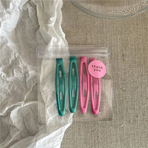 Detail of 4-piece teal and pink snap hair clips in a gift bag with thank you sticker