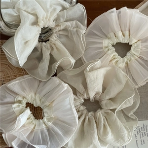 Détail de chouchous élégants en organza crème avec texture plissée et translucide