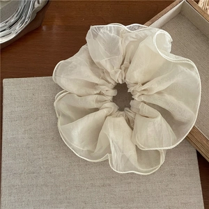Détail d'un chouchou élégant en organza blanc cassé avec coutures fines sur fond rustique