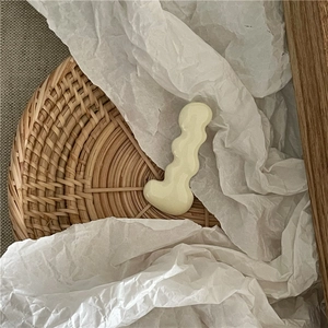 Detailed close-up of a creamy white wavy resin hairpin on a textured woven tray