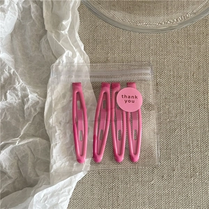 Detailed view of four pink metal hair clips in clear packaging with a thank you sticker