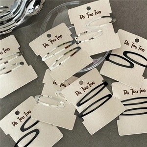 Détail de barrettes ovales minimalistes en métal argenté poli et noir mat élégant