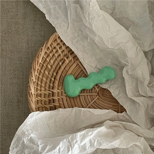 Detail of mint green wavy metal hair clip on a natural woven textured background