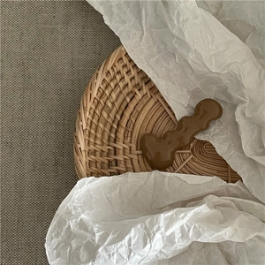 Detailed view of coffee-colored wavy hair clip with shiny resin finish on a woven tray