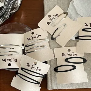 Lot de barrettes ovales en métal noir mat et argent sur support en carton blanc pur