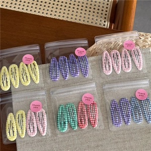 Détail de barrettes à motif vichy coloré dans un emballage transparent élégant