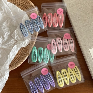 Détail de l'ensemble de barrettes à cheveux à carreaux colorés dans des sachets