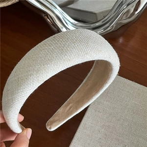 Close-up of beige fabric sponge headband showing its natural woven texture and soft suede lining