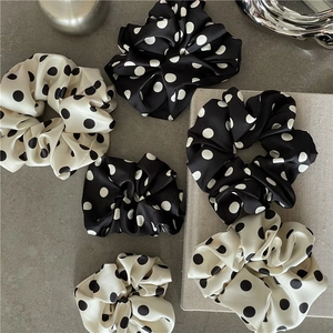 Elegant polka dot satin scrunchies set in black and white on a minimalist stone desk