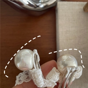 Close-up of elegant pearl hair clips with lace bows and silver metal duckbill clips