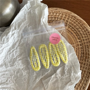 Vue détaillée de quatre barrettes à carreaux jaunes dans un emballage cadeau transparent