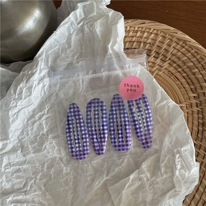 Détails de quatre barrettes à cheveux à carreaux violets et bleus dans un sachet