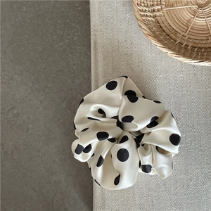 Detailed macro shot of elegant polka dot satin scrunchie with smooth silk texture