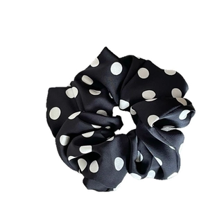 Elegant black and white polka dot satin scrunchie with soft pleated texture