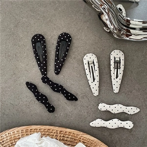 Close-up of black and white polka dot fabric hair clips with vintage water drop design