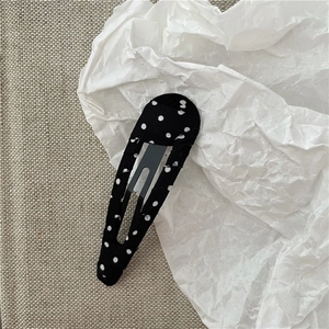 Détail de la pince à cheveux goutte enveloppée de tissu à pois noirs et blancs classiques