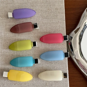 Flat lay of colorful jelly plastic hair clips on a textured woven mat background