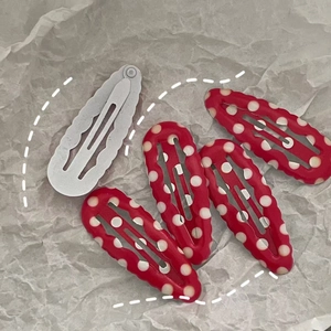 Detailopname van vijf rood-witte haarklemmen met stippen op getextureerde papieren ondergrond