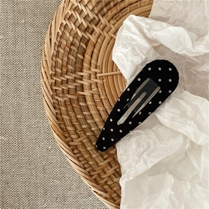 Close-up of black and white polka dot fabric BB hair clip on a textured background