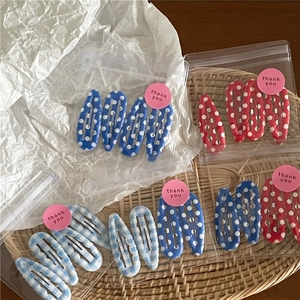 Set van BB-haarspelden met stippen en ruiten in blauw en rood op een geweven mat