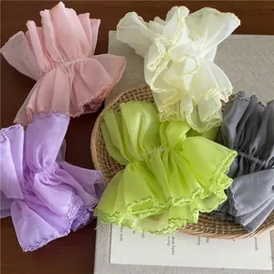 Pastel organza scrunchies in pink, beige, and purple on a rustic woven tray