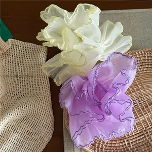 Detailed texture of lilac and yellow organza hair scrunchies with delicate ruffled edges