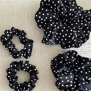 Detailed set of black and white polka dot scrunchies in various sizes on linen