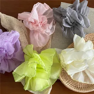 Colorful breathable mesh scrunchies in purple pink and green on a wooden tabletop