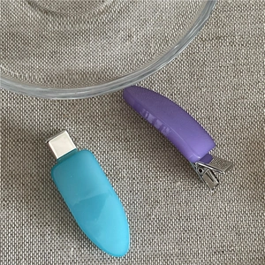 Close-up of matte resin hair clips in blue and purple on a rustic fabric background