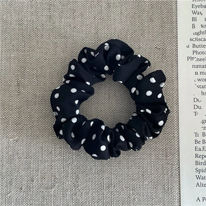 Detail of vintage black scrunchie with white polka dots on textured linen background
