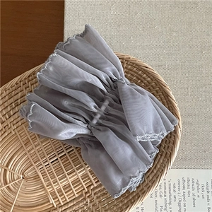 Close-up of gray mesh scrunchie with scalloped embroidery inside a woven basket