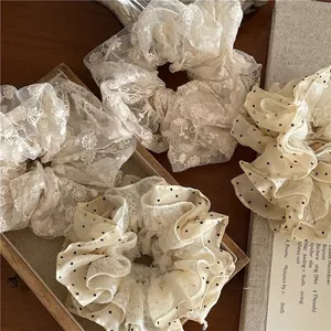 Chouchous rétro en dentelle beige et tulle à pois sur un plateau en bois avec un livre